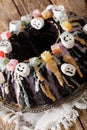 Delicious festive black Bundt cake with candied fruits, marshmallow and colored glaze close-up. vertical