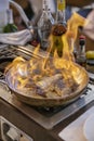 Delicious flambeed dish with large king prawns covered by large flames, a refined experience with great multisensory appeal