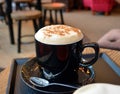 Delicious foamy cappuccino on a black cup