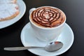 Delicious foamy cappuccino on a white cup on a plate.