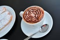 Delicious foamy cappuccino on a white cup on a plate.