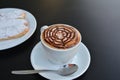 Delicious foamy cappuccino on a white cup on a plate.