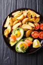 Delicious food: Baked avocado stuffed with eggs and salmon, fresh tomatoes and potato close-up. Vertical top view Royalty Free Stock Photo