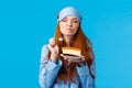 Delicious food, lifestyle and people concept. Delighted and happy cute redhead female in pyjama and sleep mask, close