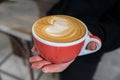 Delicious and fragrant cappuccino in the hand of a barista girl in a cozy coffee shop