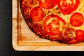 Delicious fragrant hot pizza on a wooden board on a wooden black table
