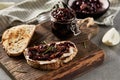 Delicious French Appetizer Freshly Cooked Onion Confit on toast with cream cheese and thyme. Wood board and jar with