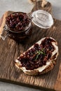 Delicious French Appetizer Freshly Cooked Onion Confit on toast with cream cheese and thyme. Wood board and jar with