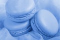 Delicious french dessert. Three gentle soft pastel blue cakes macaron or macaroon on airy fabric