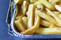 Delicious French fries in an aluminum container on a black background