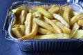 Delicious French fries in an aluminum container on a black background