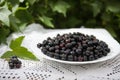 delicious and fresh black currant in a white Cup on a Lacy rustic tablecloth on a wooden background Royalty Free Stock Photo