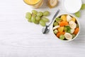 Delicious fresh fruit salad in bowl on white wooden table, flat lay. Space for text Royalty Free Stock Photo