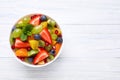 Delicious fresh fruit salad in bowl on white wooden table, top view. Space for text Royalty Free Stock Photo