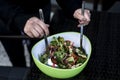 Delicious fresh healthy salad in a green bowl mixed by a woman hands with salad spoon food Royalty Free Stock Photo