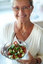 Delicious and fresh. Healthy senior woman holding a glass bowl filled with fresh salad. Royalty Free Stock Photo