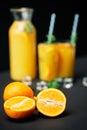 Delicious fresh orange juice with ice, mint and fruits on black table background. Royalty Free Stock Photo