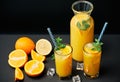 Delicious fresh orange juice with ice, mint and fresh fruits on black table background Royalty Free Stock Photo