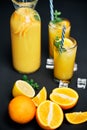 Delicious fresh orange juice with ice, mint and fresh fruits on black table background Royalty Free Stock Photo