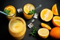 Delicious fresh orange juice with ice, mint and fresh fruits on black table background Royalty Free Stock Photo