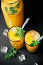 Delicious fresh orange juice with ice, mint and fresh fruits on black table background Royalty Free Stock Photo