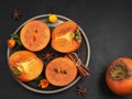 Delicious fresh persimmon fruit on a black background. Persimmon slices on a black plate. top view. Ingredients and spices for