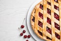 Delicious fresh pie and cherries on white wooden table, flat lay. Space for text Royalty Free Stock Photo