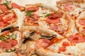 Delicious fresh pizza cut into pieces with cheese, sausage, pepperoni, bacon and mushrooms close up. High-calorie food Royalty Free Stock Photo