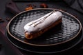 Delicious fresh profiterole or eclair with chocolate on a black ceramic plate Royalty Free Stock Photo