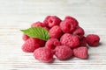 Delicious fresh ripe raspberries with leaves on white wooden table, closeup Royalty Free Stock Photo