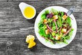 Delicious fresh salad of salami and mixed lettuce leaves - baby spinach, arugula, chard in a white dish on the old wooden table, t Royalty Free Stock Photo