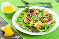 Delicious fresh salad of salami and mixed lettuce leaves - baby spinach, arugula, chard in a white dish on the old wooden table, t Royalty Free Stock Photo