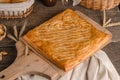 Delicious fresh square pie stuffed with curly dough decorations on wooden