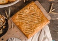 Delicious fresh square pie stuffed with curly dough decorations on wooden