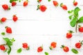 Delicious fresh strawberries and leaves of mint on white wooden background, top view. Flat lay, copy space. Ugly organic
