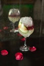 Close up drink shot of a delicious fresh yellow red cocktail with ice, a cucumber slice in a transparent wine glass standing on a Royalty Free Stock Photo