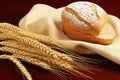 Delicious freshly baked white bread and golden sheaves of wheat on rustic wooden table