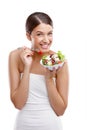 Delicious freshness. Portrait of a beautiful young woman standing with a bowl of salad against a white background.