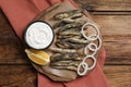 Delicious fried anchovies with onion rings, sauce and slice of lemon served on wooden table, top view. Space for text Royalty Free Stock Photo