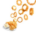 Delicious fried crispy onion rings falling in plate on white Royalty Free Stock Photo