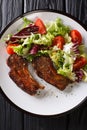 Delicious fried lamb chops served with fresh vegetable salad close-up on a plate. Vertical top view Royalty Free Stock Photo