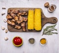 Delicious fried lamb ribs on a cutting board, with corn, spices, hot sauce on white wooden rustic background top view close up Royalty Free Stock Photo