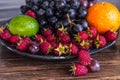 Delicious fruits salad in plate on table, lime, raspberry, grapes Royalty Free Stock Photo