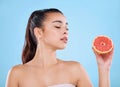 Delicious and full of goodness. Studio shot of an attractive young woman posing with half a grapefruit against a blue Royalty Free Stock Photo