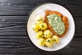 Delicious German food schnitzel with boiled new potatoes and the famous Frankfurt green sauce close-up in a plate. horizontal top