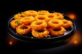 Delicious golden battered, breaded and deep fried crispy onion rings on black wooden table