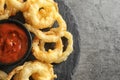 Delicious golden crispy onion rings and sauce on gray background, top view Royalty Free Stock Photo