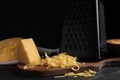Delicious grated cheese on wooden board against background