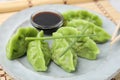 Delicious green dumplings (gyozas) and soy sauce on plate, closeup