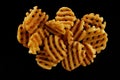 Delicious grid cut potato chips on black background